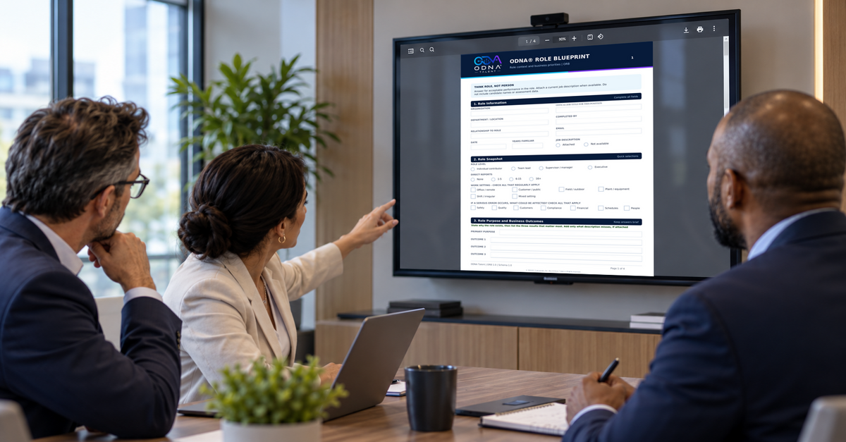 ODNA Talent branded article image showing three leaders reviewing an actual ODNA Role Blueprint page on a meeting-room screen.